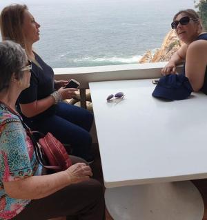 three people sitting at a table looking at the ocean