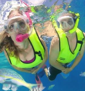 two women in the water with breathing masks and fish
