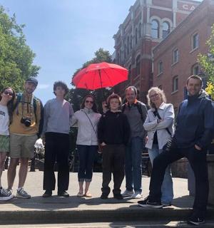 一群人站在喷泉旁边,手里拿着一把红伞