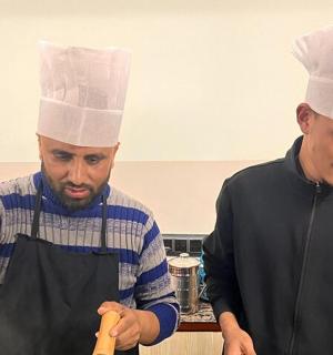 两个戴着厨师帽的男人在厨房里准备食物