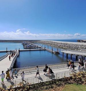 a group of people walking on a pier next to the water