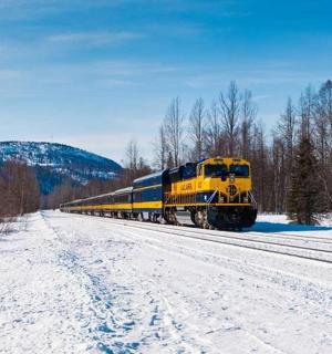 a yellow and blue train on the tracks in the snow