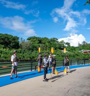 a group of people standing on a bridge with paddles
