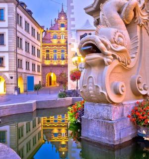 ein Brunnen in einer Stadt mit Gebäuden und einem Kanal