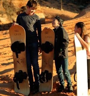 三个年轻人站在沙滩上玩滑板