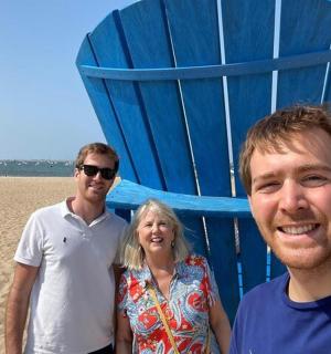 two men and a woman standing next to a blue beach chair