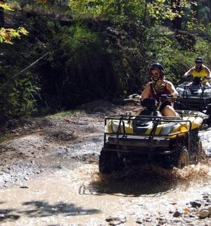 two people riding on atvs on a dirt road