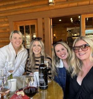 skupina žen sedících u stolu s vinnými sklenicemi