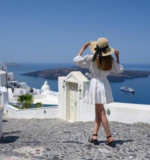 一位身穿白色连衣裙、头戴白色帽子的女子凝视着大海