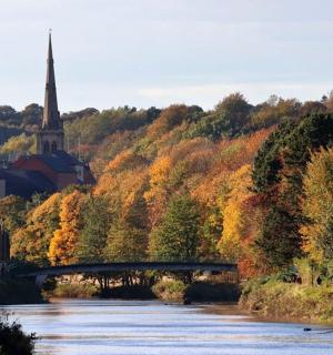 a river with a bridge and a church on a hill