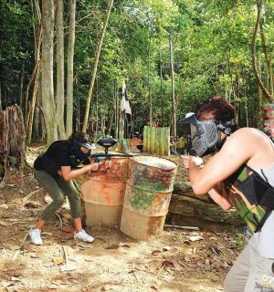 两个人站在森林里,周围有木桶