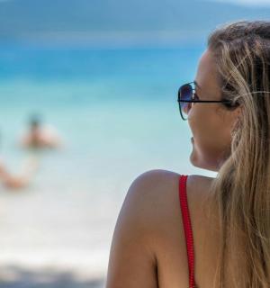 a woman wearing glasses standing at the beach