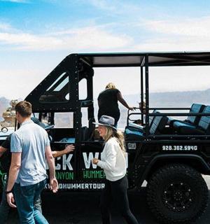a group of people standing around a jeep at the grand canyon