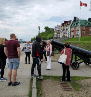 a group of people standing on a sidewalk looking at a cannon