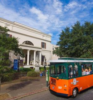 an orange and green bus parked in front of a building