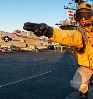 a man is standing on an aircraft carrier