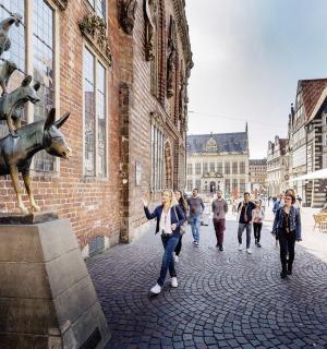 a group of people walking down a street with a statue