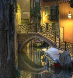 a canal with a bridge and a boat in the water
