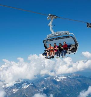 skupina lidí jedoucích na lyžařském vleku v oblacích