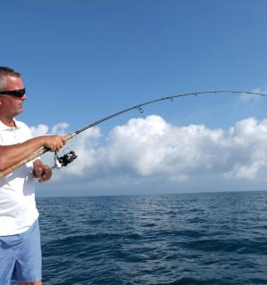 a man standing on a boat holding a fishing rod