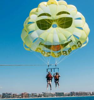 two people are riding on a parachute over the water