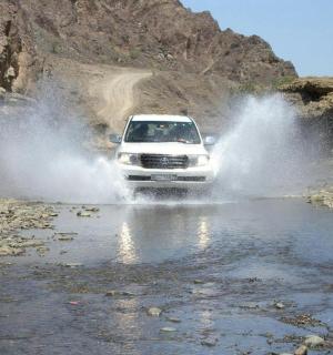 a white truck driving through a river in the mud