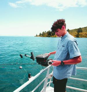 一名男子站在船上在水上钓鱼