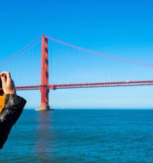 a woman taking a picture of the golden gate bridge