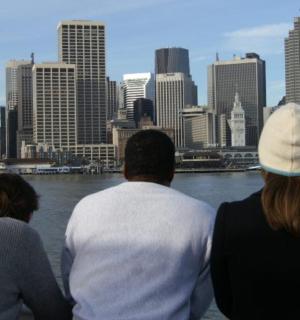 three people sitting on a boat looking at the city