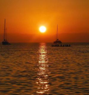two boats floating in the ocean at sunset