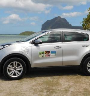 a white car parked on a beach near the water