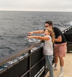 muž a dívka stojící na boku lodi