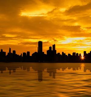 panorama města při západu slunce nad vodní plochou