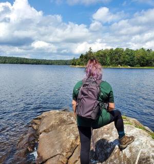 a person sitting on a rock by a lake