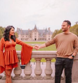 a man and a woman holding hands over a fence