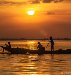 日落时分,三个人在水上的船上