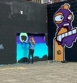 一位女士站在墙前,手里拿着风筝