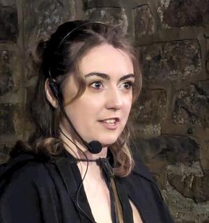 eine Frau steht vor einer Backsteinmauer