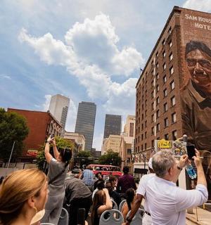 dav lidí stojících na ulici s plakátem muže