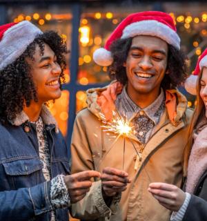 三个戴着圣诞帽、手里拿着烟火棒的人