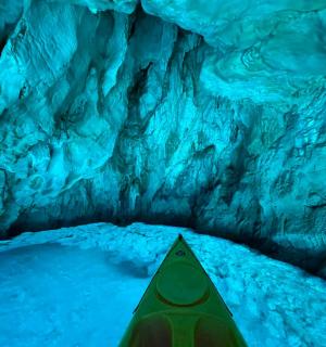 a kayak in front of a blue ice cave
