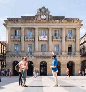 een groep mensen die voor een gebouw met een klokkentoren staan