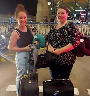 两名女子带着行李站在机场