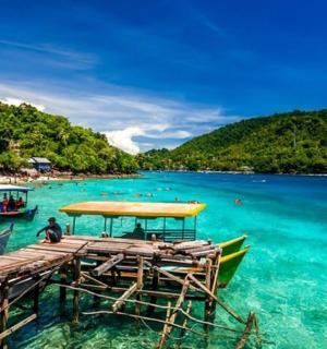 a dock with boats in the water next to a beach