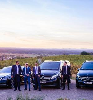 eine Gruppe von Männern in Anzügen steht neben zwei Autos