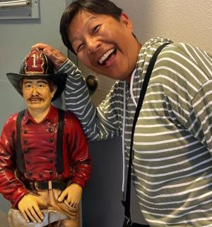 muž stojící vedle sochy muže v klobouku