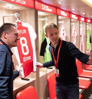 两名男子站在更衣室里，身穿球衣