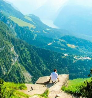 a man sitting on a rock overlooking a valley