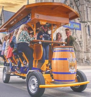 skupina lidí jedoucích na autě z pivních sudů