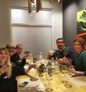 skupina lidí sedících kolem stolu a popíjejících víno